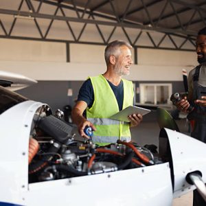 Aviation mechanics are discussing aircraft engine components during a repair in a hangar